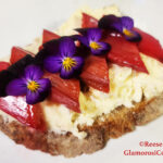 This horizontal photo show the completed recipe for Honey-roasted Rhubarb Toast with Brie by Reese Amorosi for GlamorosiCooks.com