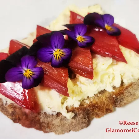 This horizontal photo show the completed recipe for Honey-roasted Rhubarb Toast with Brie by Reese Amorosi for GlamorosiCooks.com