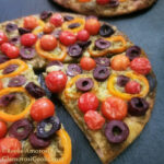 This photo shows the completed recipe for Easy Flatbread Pizza by Reese Amorosi for GlamorosiCooks.com. The flatbread is topped with pesto, cheese, tomatoes, peppers and olives.